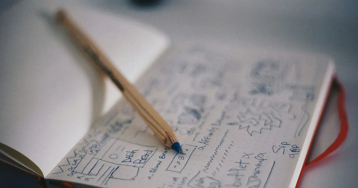 Notizbuch mit App-Wireframe-Skizzen und Bleistift