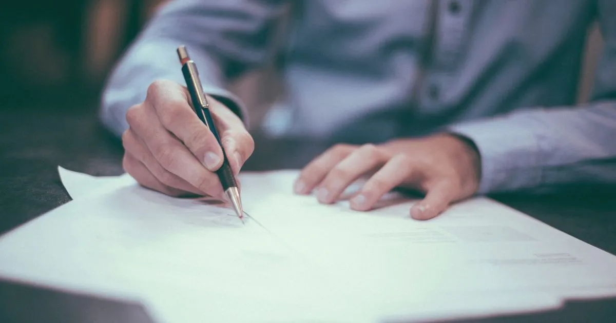 Eine Person unterschreibt Antragsunterlagen mit einem Stift
