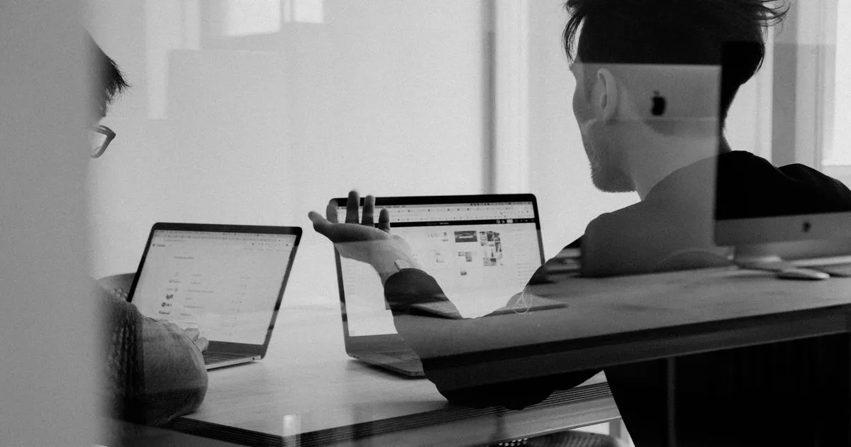 Zwei Entwickler besprechen sich an Laptops im Büro